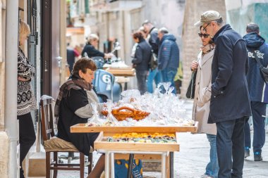 Bari, İtalya - 5 Nisan 2023: Bari 'nin eski kentinde turistlere taze orkestra veya orecchietta satan yaşlı kadın, buğday ve suyla yapıldı, el yapımı makarna tipik Puglia veya Apulia, İtalya