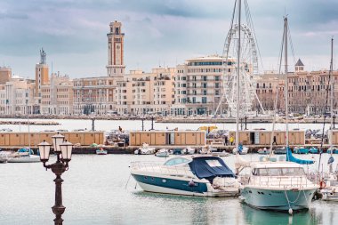 Bari, İtalya - 5 Nisan 2023: Bari, Puglia veya Apulia Panoraması, Güney İtalya Akdeniz, tekneler, sokak lambaları, dönme dolap ve deniz kenarında faşist mimari