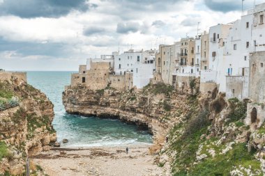 Polignano a Mare, Bari, İtalya. Kayalık kayalıkların üzerine inşa edilmiş eski bir kasaba. Geleneksel evleri, dramatik bulutlu gökyüzü ve güzel Akdeniz manzaralı seyahat konsepti
