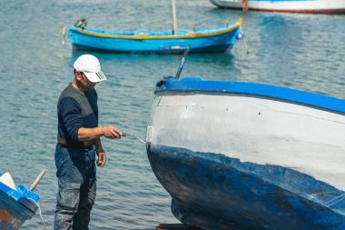 Bari, Puglia, İtalya - 8 Nisan 2023: Puglia İtalya 'nın Bari limanındaki eski bir ahşap balıkçı teknesini tamir eden ve boyayan balıkçı