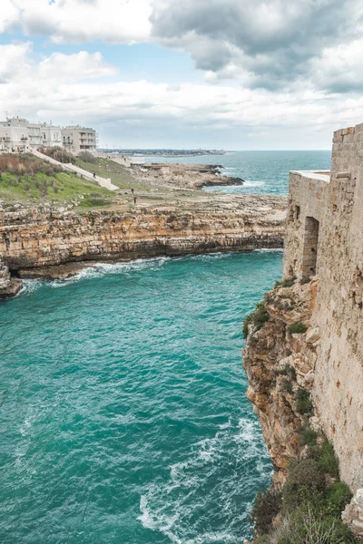 Polignano a Mare, Bari, İtalya. Kayalık kayalıkların üzerine inşa edilmiş eski bir kasaba. Geleneksel evleri, dramatik bulutlu gökyüzü ve güzel Akdeniz manzaralı seyahat konsepti