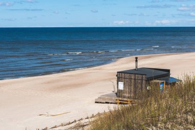 Baltık Denizi manzaralı beyaz kumlu bir sahilde güzel, modern ahşap sauna ve Litvanya, Klaipeda 'da bulutlu gökyüzü.