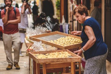 Bari, İtalya - 5 Haziran 2023: Bari eski kasabasındaki turistlere taze orkide ya da orecchietta satan yaşlı bir kadın, porselen buğday ve sudan yapılan el yapımı makarna, tipik Puglia veya Apulia, İtalya