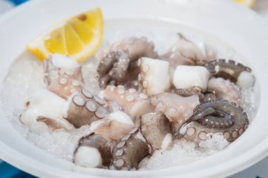 Bari, Puglia, İtalya 'daki bir balık pazarında limon ve buzla yenmeye hazır taze ahtapot tabağı.