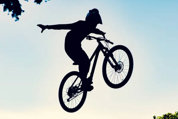 stock image Silhouette of a biker performing an extreme dirty jump with a bmx bike against the sky 