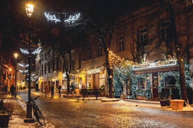Vilnius, Lithuania - December 5 2023: Beautiful cozy Christmas decorations, wreath, garlands and lights in Vilnius old town, capital of Lithuania, Europe, by night with street lamps and bike