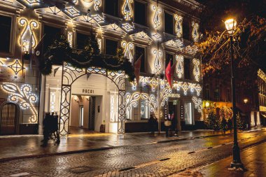 Vilnius, Lithuania - December 5 2023: Beautiful entrance and windows of a hotel with cozy Christmas decorations, wreath, garlands and lights in Vilnius old town, capital of Lithuania, Europe