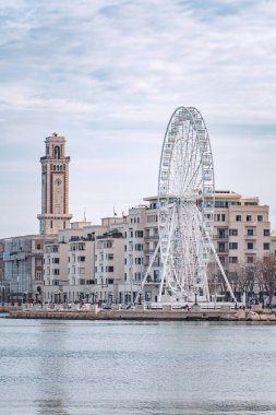 Bari, Puglia, İtalya - 30 Aralık 2023: Bari, Puglia veya Apulia Panoraması, Güney İtalya, Akdeniz, sokak lambaları, dönme dolap ve deniz kenarında faşist mimari, dikey