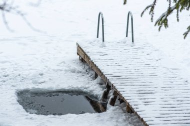 Soğuk terapi ve buz banyosu için karla kaplı donmuş bir göldeki delikte. Wim Hof Yöntemi, soğuk terapi, solunum teknikleri, yoga ve meditasyon