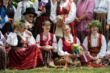 Vilnius, Litvanya - 7 Temmuz 2024: Ülke çapında Litvanya Şarkı ve Dans Festivali sırasında geleneksel giysileri içinde Letonya bayrağı taşıyan bir grup 