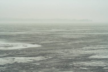 Arka planda donmuş göl ve dumanı tüten sisli ormanla harika bir ilkbahar manzarası.