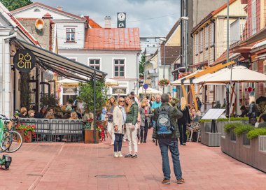 Parnu, Estonya - 17 Ağustos 2025: Parnu Eski Kentinde kaldırım taşı patikası, açık kafeler, restoranlar, dükkanlar ve eski evler boyunca yürüyen insanlar ile dolu bir cadde