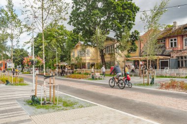 Parnu, Estonya - 17 Ağustos 2025: Parnu Eski Kentinde kaldırım taşı patikası, açık kafeler, restoranlar, dükkanlar ve eski evler boyunca yürüyen insanlar ile dolu bir cadde