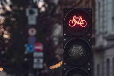 Alacakaranlıkta kentsel sokak arkaplanına karşı aydınlatılmış kırmızı bisiklet trafik ışığı yakın plan, şehir çevresindeki bisikletçiler için durak anlamına gelir
