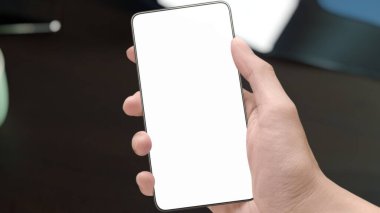 Ofis masasının üst perspektifindeki modern akıllı telefon aygıtını kullanan, sosyal medya mesajlarını okuyan ve e-postaları kontrol eden erkeklerin yakın plan seçici görüntüsü. Ürün sahneleme alanı maketi.