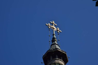 Metal Orthodox cross on church tower towards blue sky, signifies connection between heaven and earth, upward aspiration, righteousness of life illuminated by faith