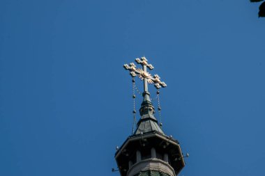 Metal Orthodox cross on church tower towards blue sky, signifies connection between heaven and earth, upward aspiration, righteousness of life illuminated by faith