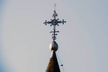 Metal Orthodox cross on church tower towards blue sky, signifies connection between heaven and earth, upward aspiration, righteousness of life illuminated by faith