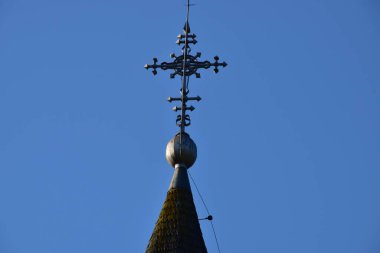 Metal Orthodox cross on church tower towards blue sky, signifies connection between heaven and earth, upward aspiration, righteousness of life illuminated by faith
