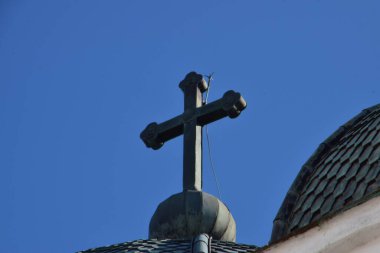 Metal Orthodox cross on church tower towards blue sky, signifies connection between heaven and earth, upward aspiration, righteousness of life illuminated by faith