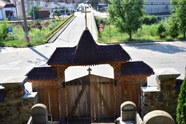 Maramures Gate, meşe ağacından yapılmış, farklı geleneksel çiçek motifleriyle oyulmuş üç sütuna sabitlenmiş, kapı kiremitlerle kaplı.