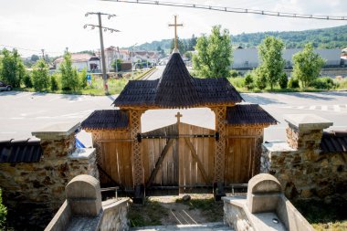 Maramures Gate, meşe ağacından yapılmış, farklı geleneksel çiçek motifleriyle oyulmuş üç sütuna sabitlenmiş, kapı kiremitlerle kaplı.