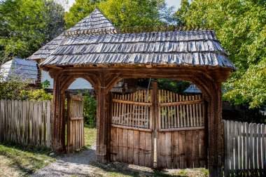 Maramures Gate, meşe ağacından yapılmış, genellikle farklı çiçek motifleriyle oyulmuş en az üç sütun, üst kapı eşiği kiremitlerle kaplı.