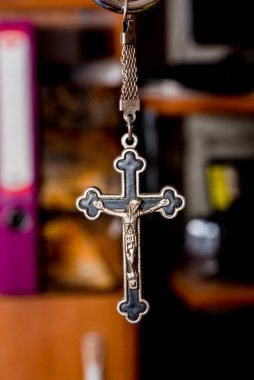 Karanlık bir arka planda metal haç. Din kavramı. Hristiyan sembolleri. Ortasında İsa figürü olan erkek haçı, gümüşten yapılmış, kordonla takılmış. Zincirle de takılabilir.