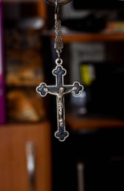 Karanlık bir arka planda metal haç. Din kavramı. Hristiyan sembolleri. Ortasında İsa figürü olan erkek haçı, gümüşten yapılmış, kordonla takılmış. Zincirle de takılabilir.