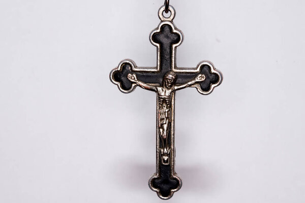 Metal cross on a dark background. Concept of religion. Christian symbols. Male crucifix with figure of Jesus Christ in the center, made of silver, worn with a cord. It can also be worn with a chain