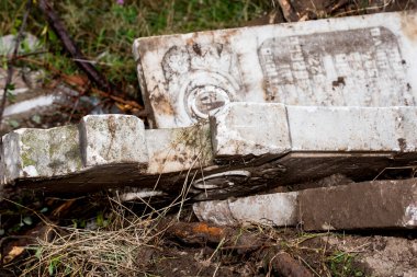 İnşaat alanında kırık mermer haçlar. Bir mezarlığın yıkılması. Mezarlıkta terk edilmiş bir mezar taşı, yakın plan fotoğraf.