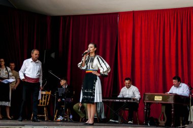 Gorj ilçesinden gelen halk müziği sanatçıları geometrik ve çiçek desenli parlak renkli geleneksel ulusal kostümler giyiyorlar..