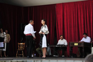 Gorj ilçesinden gelen halk müziği sanatçıları geometrik ve çiçek desenli parlak renkli geleneksel ulusal kostümler giyiyorlar..