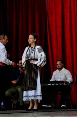 Gorj ilçesinden gelen halk müziği sanatçıları geometrik ve çiçek desenli parlak renkli geleneksel ulusal kostümler giyiyorlar..