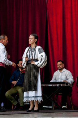 Gorj ilçesinden gelen halk müziği sanatçıları geometrik ve çiçek desenli parlak renkli geleneksel ulusal kostümler giyiyorlar..