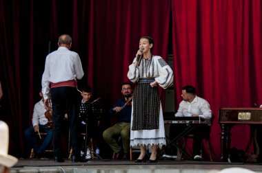 Gorj ilçesinden gelen halk müziği sanatçıları geometrik ve çiçek desenli parlak renkli geleneksel ulusal kostümler giyiyorlar..