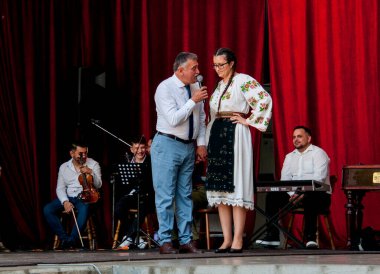 Gorj ilçesinden gelen halk müziği sanatçıları geometrik ve çiçek desenli parlak renkli geleneksel ulusal kostümler giyiyorlar..