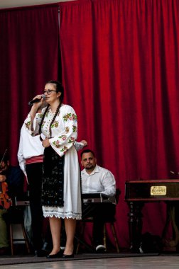 Gorj ilçesinden gelen halk müziği sanatçıları geometrik ve çiçek desenli parlak renkli geleneksel ulusal kostümler giyiyorlar..