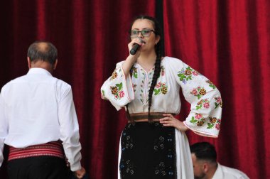 Gorj ilçesinden gelen halk müziği sanatçıları geometrik ve çiçek desenli parlak renkli geleneksel ulusal kostümler giyiyorlar..