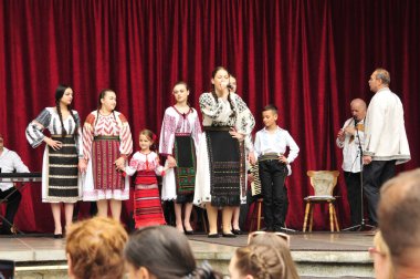 Gorj ilçesinden gelen halk müziği sanatçıları geometrik ve çiçek desenli parlak renkli geleneksel ulusal kostümler giyiyorlar..