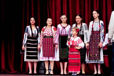 Gorj ilçesinden gelen halk müziği sanatçıları geometrik ve çiçek desenli parlak renkli geleneksel ulusal kostümler giyiyorlar..