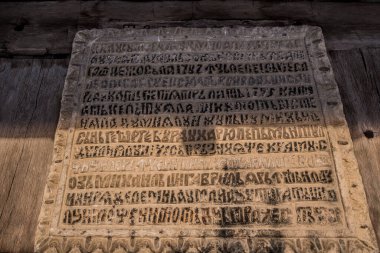 Taş duvara eski ahşap harfler kazınmış.