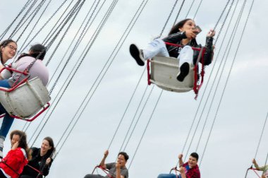 Genç kızlar lunaparkta atlıkarıncaya biniyorlar.