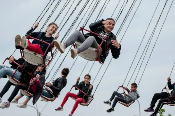 Bir grup mutlu arkadaş bulutlu bir günde lunaparkta eğleniyorlar..