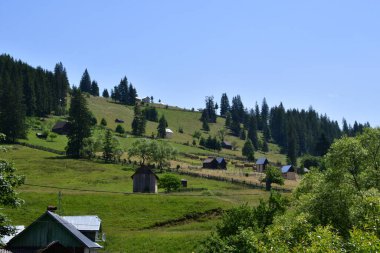 Dağları olan güzel bir manzara ve arkasında mavi bir gökyüzü.