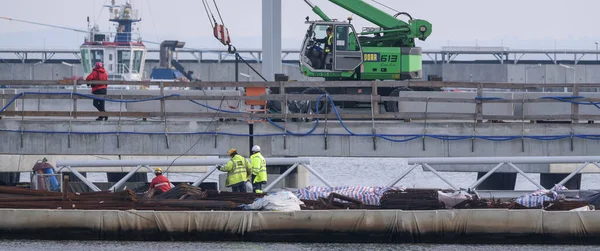 stock image SWINOUJSCIE, WEST POMERANIAN - POLAND - 2022: Workers and construction machinery on a sea port gas terminal building site 