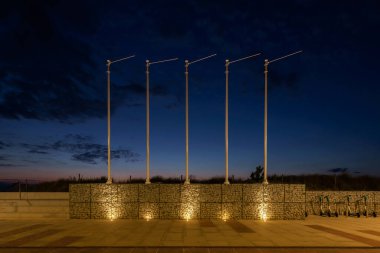 PROMENADE - Bayraklar ve deniz kenarında gün batımında yürüyen bir patikada bir Gabion