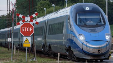 MILOGOSZCZ, Batı Pommeranya - POLAND - 15 Temmuz 2023: Demiryolu geçidinde dur işareti ve hareket halindeki ekspres tren