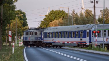 TYMIEN, BATI POLAND - 15 HAZİRAN 2023: Bir ekspres tren paraşütçülerle bir demiryolu geçidinden geçiyor
