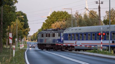 TYMIEN, BATI POLAND - 15 HAZİRAN 2023: Bir ekspres tren paraşütçülerle bir demiryolu geçidinden geçiyor